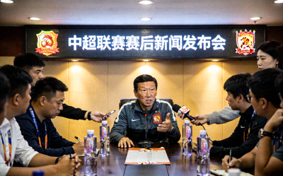 中超联赛赛后新闻发布会现场，主教练正在接受媒体采访