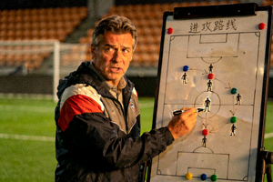 足球教练在战术板上绘制进攻路线图，分析比赛战术