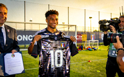 足球运动员在训练场上进行签约仪式，手持新球队球衣